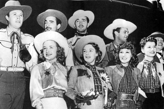 Promoting the premiere of “Dodge City” (‘39) in Dodge City, KS are Warner Bros. contractees (back row) Wayne Morris, Gilbert Roland, John Payne, Allan Jones, Frank McHugh. (front row) Priscilla and Rosemary Lane, Jean Parker, Frances Robinson. 