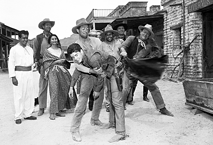 Dean Martin and John Wayne seem to be giving Ricky Nelson a “chaps spanking” on the set of “Rio Bravo”. 