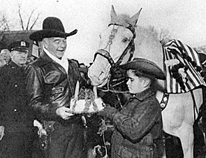 A young fan feeds a carrot cake to Hopalong Cassidy's horse Topper.