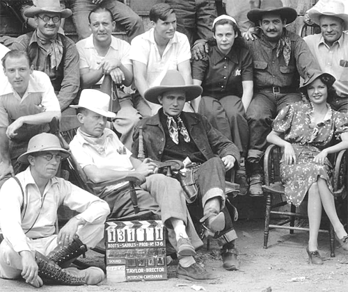 Cast and crew of "Tex Rides With the Boy Scouts" ('38 Grand National). Identified are Ed Cassidy (top row left), Charlie King (top row, 2nd from right), cameraman Gus Peterson (bottom left), director Ray Taylor (in chair), Tex Ritter, Marjorie Reynolds. (Thanx to Ed Tabor, Chuck Anderson.)