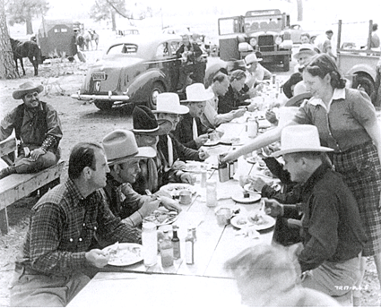 The cast of "Take Me Back to Oklahoma" ('40) takes a lunch break. Tex Ritter is the second man on the left side of the table. B-Western badman Olin Francis sits on a bench at the left. (Courtesy Terry Swindol.) 