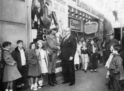 In February 1956, Clayton Moore as The Lone Ranger is greeted in Ft. Worth, TX, by Ray Jones, manager of a local theater, and a throng of young kids.