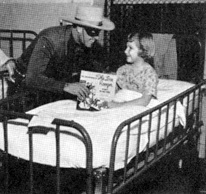 Clayton Moore as the Lone Ranger talks with a crippled child at Charity Hospital in New Orleans.