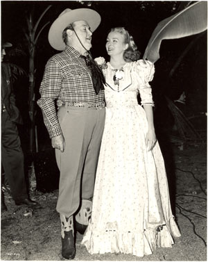 “Riders of Death Valley” producer Henry McCrae and leading lady Jeanne Kelly take a break between serial scenes.