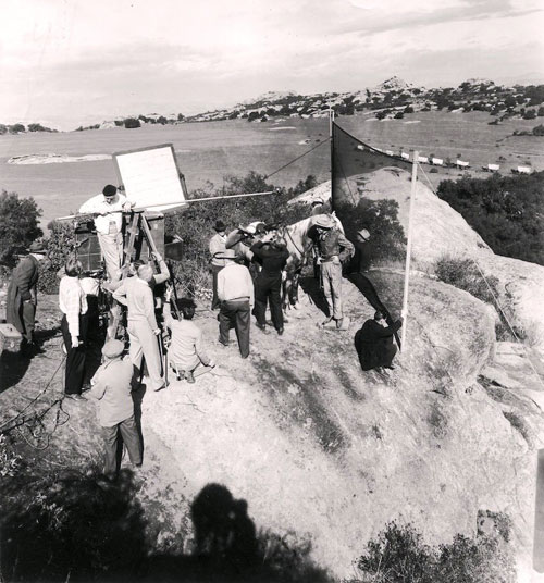 Behind the scenes shot while filming “California” in 1946. Released by Paramount in ‘47. Ray Milland in buckskins by the horse. Film was directed by John Farrow who is likely the man with his elbow bent standing by the camera. (Thanx to Jerry Whittington.)